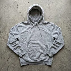 A grey hoodie laid flat on raw concrete, shot from overhead.