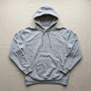 A grey hoodie laid flat on a linen cloth.