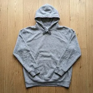 A grey hoodie laid flat on pale wooden boards.
